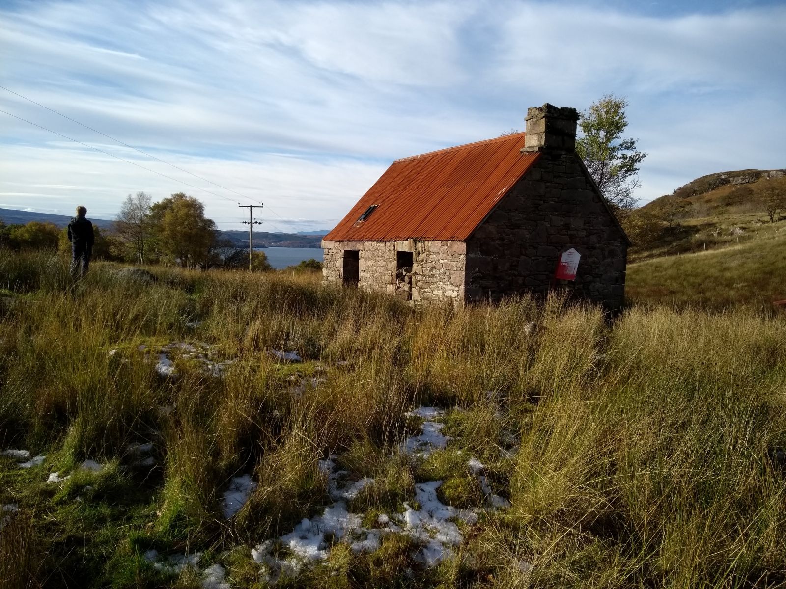 Old building in the highlands, tall grass, man on hill